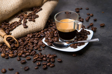 real italian espresso coffee in a glass cup on a black floor with coffee beans cutting light