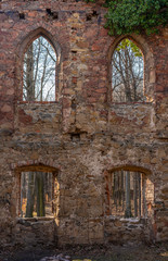 Fototapeta na wymiar Ancient brick wall with windows in an abandoned nature setting