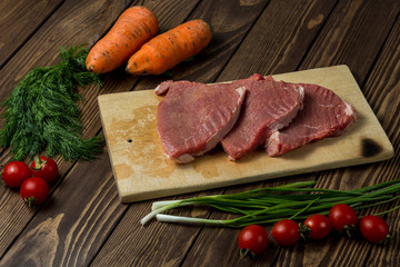 raw meat on a cutting board. beef steak with herbs, cherry tomatoes,