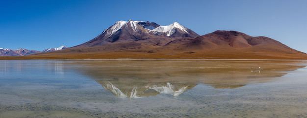Panoramic shot of a lake near Uyuni, Bolivia . Mountain range view. Dramatic mountain landscape wilderness with water reflexions and flamingos . Landscape with beautiful mountains background. 