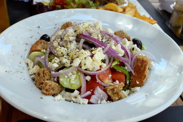 Greek salad dressed with olive oil and herbs