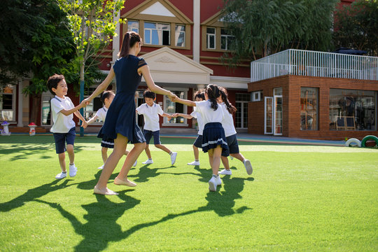 Teacher and students playing in kindergarten playground - Powered by Adobe