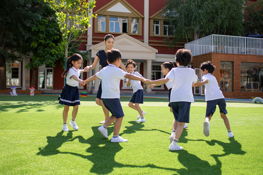 Teacher and students playing in kindergarten playground