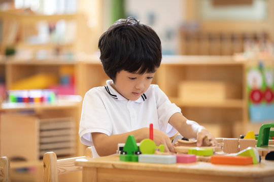 Little boy playing train set in classroom