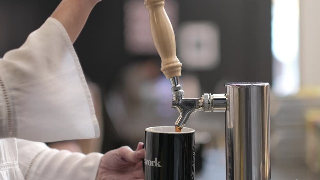 Woman's Hands Pour Hot Coffee From Tap in Modern Co-working Space 