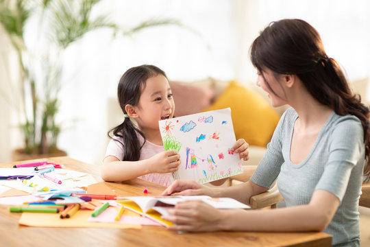 Happy mother and daughter drawing at home