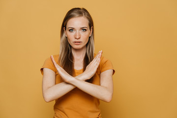 Confident redhead pretty woman in orange t-shirt, shows gesture sign stop, crossing her arms, wants...