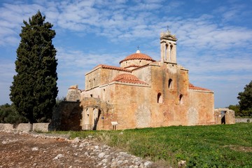 Fototapeta na wymiar Metamorphosis Sotiros church in Pylos Nestor Palace (Niokastro Navarino) and trees in Greece at sunny day with blue sky
