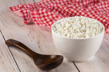 Organic curd in a white ceramic bowl with wooden spoon and red napkin on a wooden table