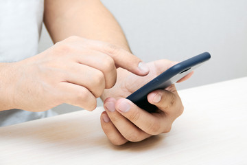A person is holding a phone and tapping the screen on a white background with copy space. Concept of lifestyle business and Internet technologies in the office