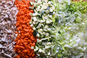 Chopped mushroom, carrot, zucchini and leek on a cutting board. Top view.