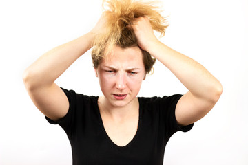 Close-up of a thoughtful, scared girl with yellow hair doing a rocker Mohawk on her head, on a white background. Informal teenagers, concept.