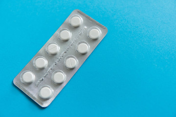 Top view on the pills in the package. White pills on blue background. Medicine, medication, painkillers, tablet, medicaments, drugs, antibiotic, vitamin, treatment, capsule, dose. Pharmacy theme.