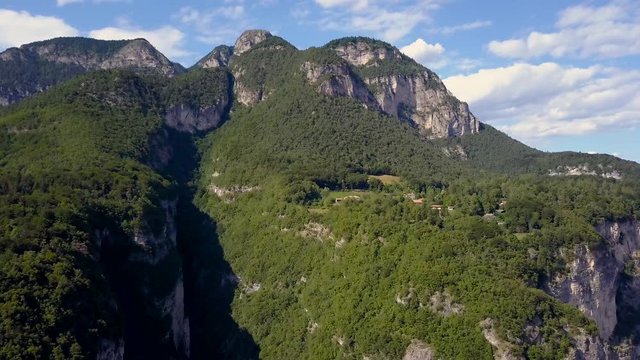 Drone slowly moves in towards a beautiful forested mountain in the European Alps. Stunning view in Trentino, Italy