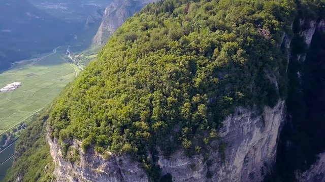 Aerial drone shot of a striking cliffside forest on a mountain in Trentino, northern Italy