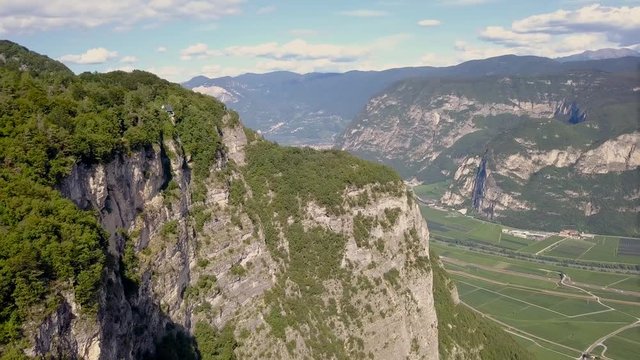 Cinematic Drone shot of a beautiful cliff on a mountain in Trentino Italy. The green mountain landscape is stunning on a bright day