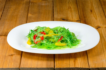 Asian style salad with cellophane noodles, sweet pepper and carrots in white plate on a wooden background