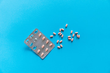 Top view on the pills removed from the pack. Pink pills on blue background. Medicine, medication, painkillers, tablet, medicaments, drugs, antibiotic, vitamin, treatment, capsule, dose. Pharmacy theme