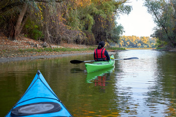 Kayaking together. Couple kayaking on the river together at autumn. View from blue kayak