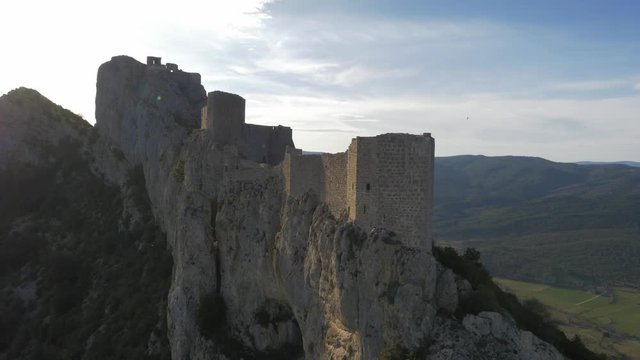 Close fly over Chateau De Peyrepertuse with dramatic cliff faces in the sun