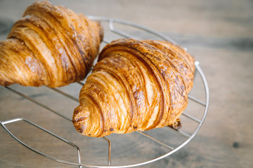 Freshly baked classic croissants on metal silver rock and wooden background. Breakfast food concept. 