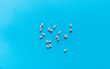 Fototapeta na wymiar Pink pills on blue background. Medicine, medication, painkillers, tablet, medicaments, drugs, antibiotic, vitamin, treatment. Pharmacy theme. Top view on the pills scattered on the blue surface.