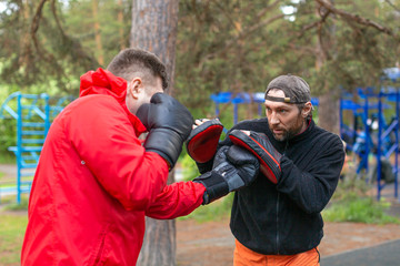 Middle-aged boxer training with coach.