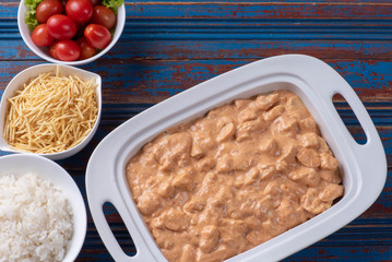 Chicken stroganoff accompanied with rice, salad and potato straw