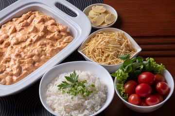 Chicken stroganoff accompanied with rice, salad and potato straw