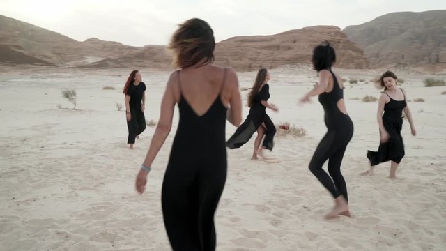 Happy women dancing ecstatic dance in desert at sunrise