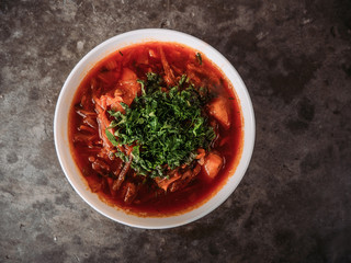 Red borsch on a black background. Borsch with vegetables and tomato. Ukrainian traditional cuisine.