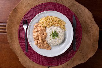 Chicken stroganoff accompanied with rice, salad and potato straw