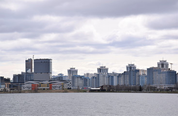 panorama of modern buildings across the river against a dark gray sky, urban architecture, urbanization
