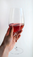 glass with rose wine in a female hand, white background