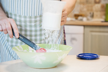 A woman preparing food in a bowl on a cutting board with a cake