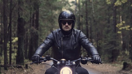 Fototapeta na wymiar Guy riding motorcycle on forest road