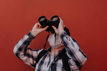 a man looks up through binoculars on a red background