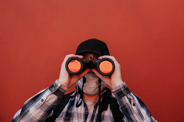 a man in a shirt look at the camera through binoculars on a red background