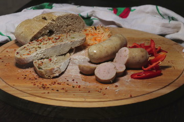 Home sausages with home bread on a wooden plate