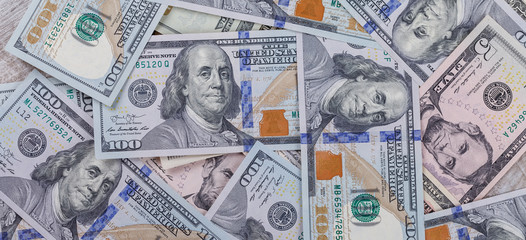 Many one hundred dollar bills are scattered on the table