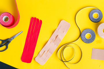Special physio tapes rolling of different colors and scissors for cutting on a yellow background. Kinesiology taping treatment.