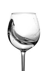 Splash of water in a wine glass on a white background. Studio shot. Water is the basis of life. The concept of a healthy lifestyle. Black and white photo