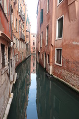 Fototapeta na wymiar Canals through narrow streets of Venice