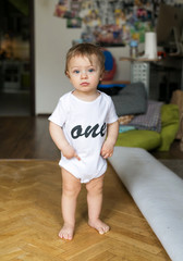 Beautiful baby birthday boy. Smiling kid with balloons in his hands laughtsand rejoices. Beautiful baby in a white shirt on a black background.