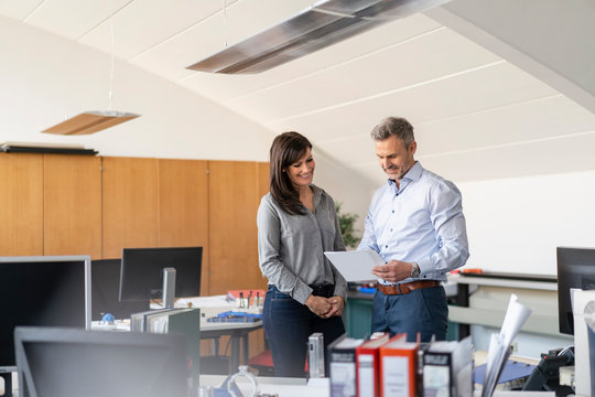 Businessman and businesswoman discussing paper in office