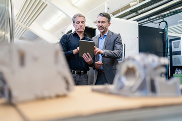 Businessmen in factory, having a meeting, using digital tablet