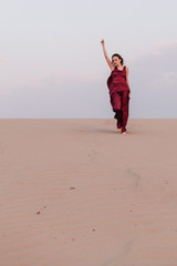 Obraz premium Girl in red dress with cloth in the wind in the desert