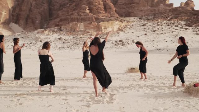 Amazing view of desert with group women practice ecstatic dance