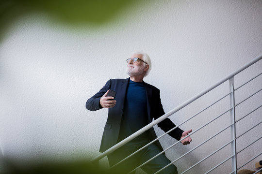 Senior man taking selfie with smartphone while posing on stairs - Powered by Adobe