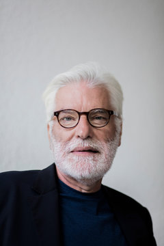 Portrait of bearded senior man with white hair wearing glasses